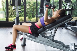 Young and beautiful woman working out with dumbbells in gym