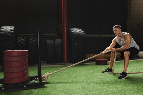 Strong sportsman during his cross training workout sled drag exercise