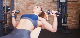 Sporty Girl doing dumbbell press on incline bench in gym