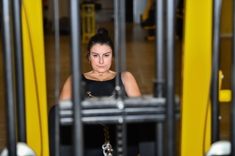 Focused looking woman uses a leg adductor machine at a gym