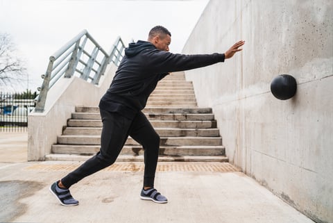 Athletic man doing wall ball exercise outdoors sport and healthy concept