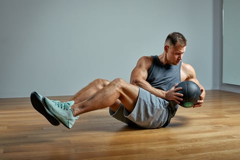 Strong man doing exercise with med ball perfect physique on grey background strength and motivation