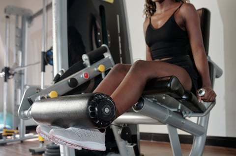 Fit young woman doing exercise on leg extension machine