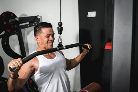 Asian man in white tank top training back muscles