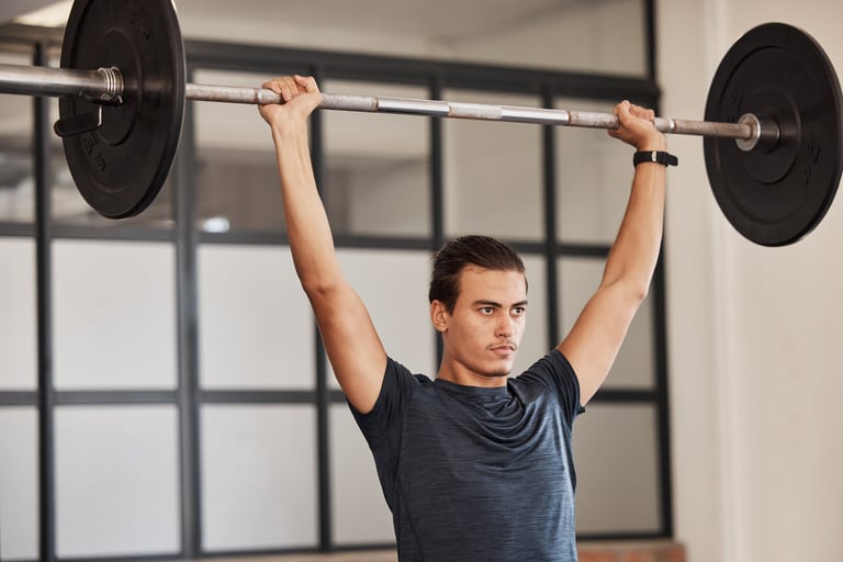 Strong man doing overhead barbell press in gym