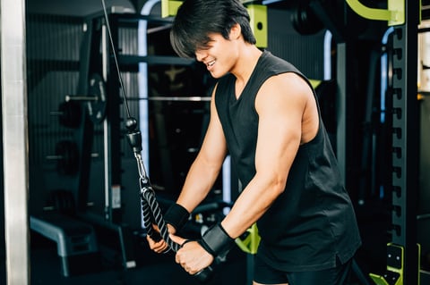Athlete exercising with cable machine using rope handles for triceps pulldowns