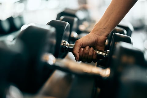 Female hand picking up a heavy dumbbell