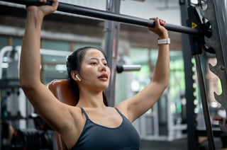 Sporty woman lifting a barbell on an incline bench press machine in a gym