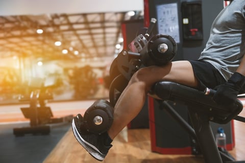 Man training legs in gym doing leg extensions on machine