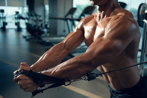 Sporty Asian man exercising on multistation at gym for arm and shoulders muscles
