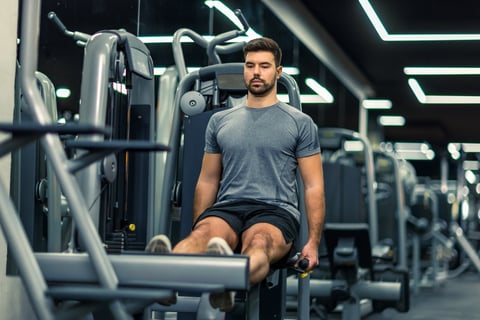 Muscular man doing exercises on a leg press machine