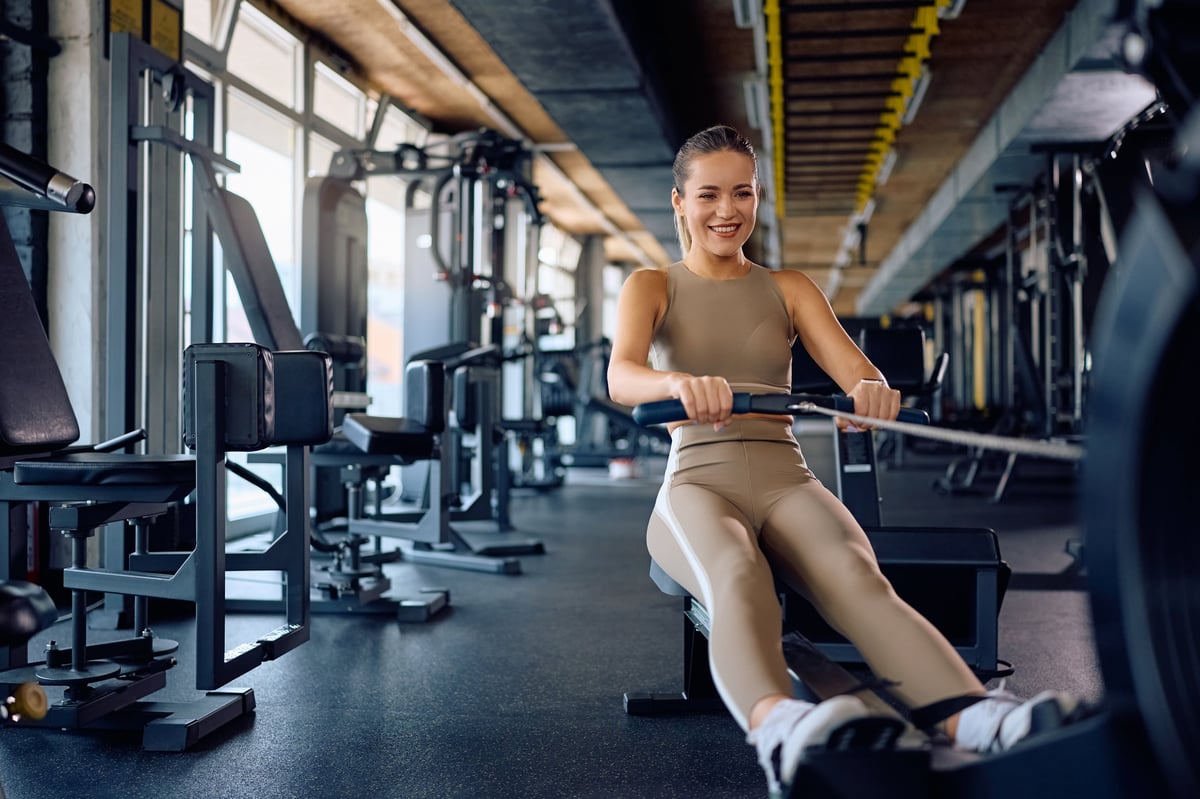 Atleta femenina sonriendo mientras se ejercita en máquina de remo