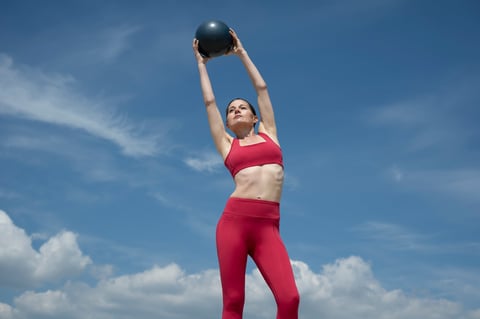 Woman Exercising Outdoors With Medicine Ball Under Clear Sky