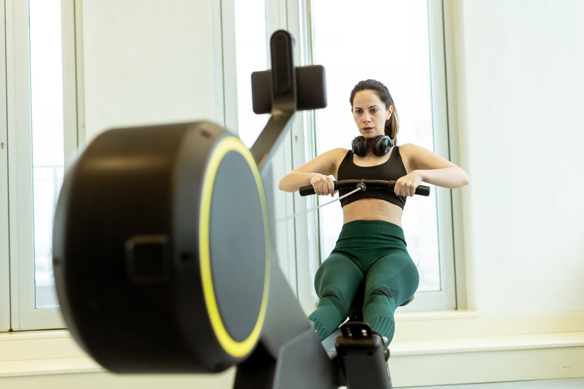 Mujer determinada remando en gimnasio moderno y brillante