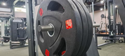 Black rubber weight plate on gym equipment with red markings