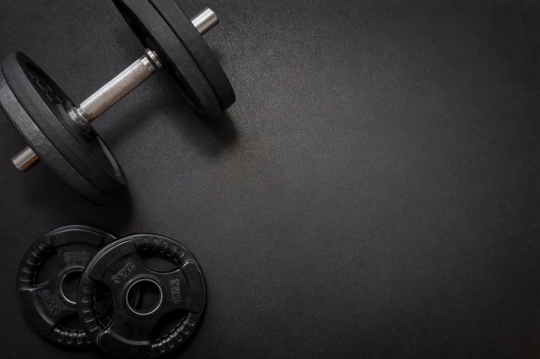 Weight training area with dumbbells and barbell on gym floor