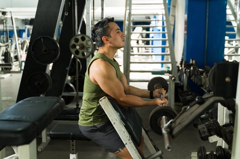 Athletic man doing arm workout on preacher curl bench