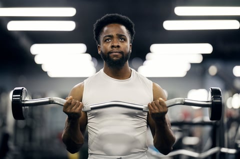 Young adult man focusing during weight training using an ez curl bar