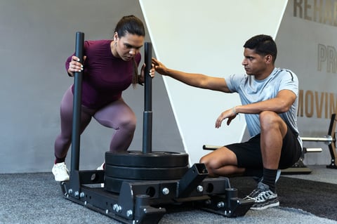 Latin american woman intensely pushing a weighted sled in a gym