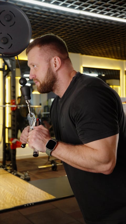 Strong male athlete focusing on arm workout in professional fitness center