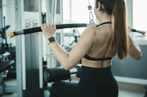 Female athlete performing lat pulldown exercise in modern gym upper body strength