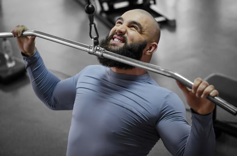 Professional athlete pulling down heavy weight during sports training