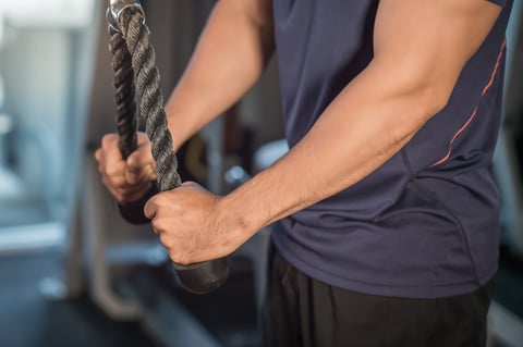 Muscular young man training triceps in the gym