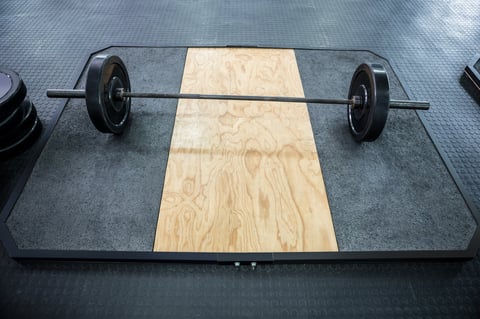 A barbell next to weights in gym