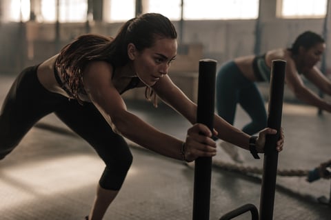 Strong young female pushing the prowler exercise equipment