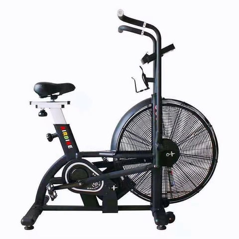 Black and white stationary exercise bike with large fan wheel, seat, handlebars, and pedals on white background