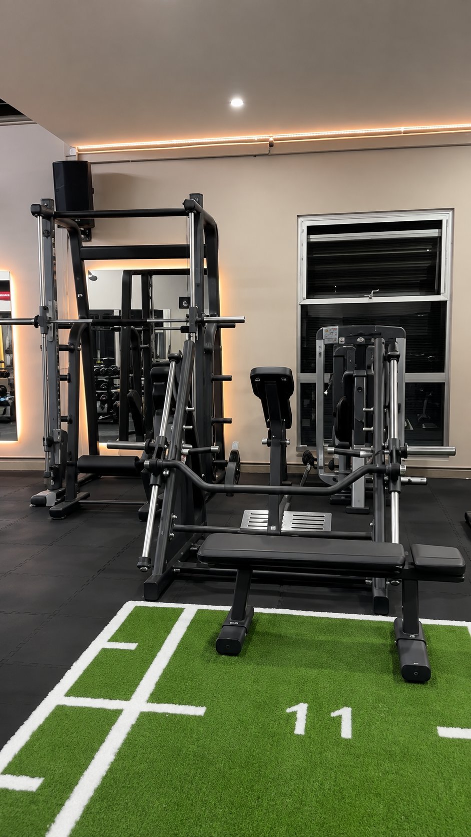 Modern gym interior with multi-station exercise equipment on artificial turf marked with yard lines