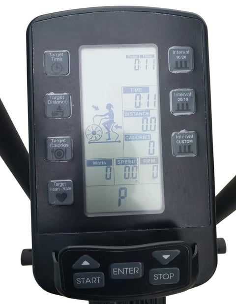 Digital exercise bike computer display showing time, distance, speed, RPM, watts, and calories with control buttons and menu options